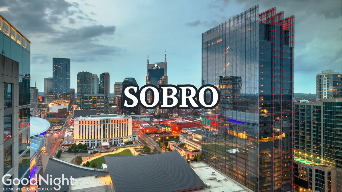 A stunning city skyline at dusk, with illuminated buildings and the 'SOBRO' logo, suggesting a vibrant urban nightlife below. The cityscape radiates energy, emphasizing the excitement of downtown Nashville after dark.