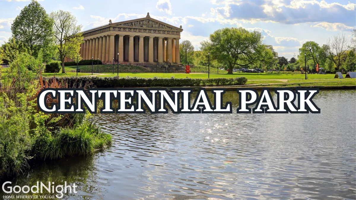 A serene view of the Parthenon-like structure across calm water, surrounded by green lawns and trees, with people enjoying walks and outdoor activities in the park-like setting.